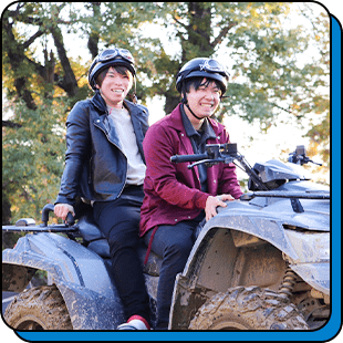 ATVに乗って笑顔を見せる社員2人